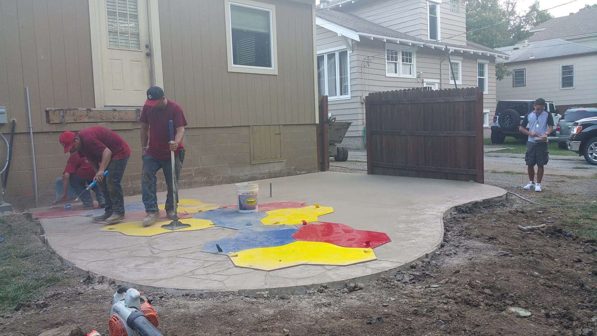 A man painting colorful shapes on a concrete surface outdoors.