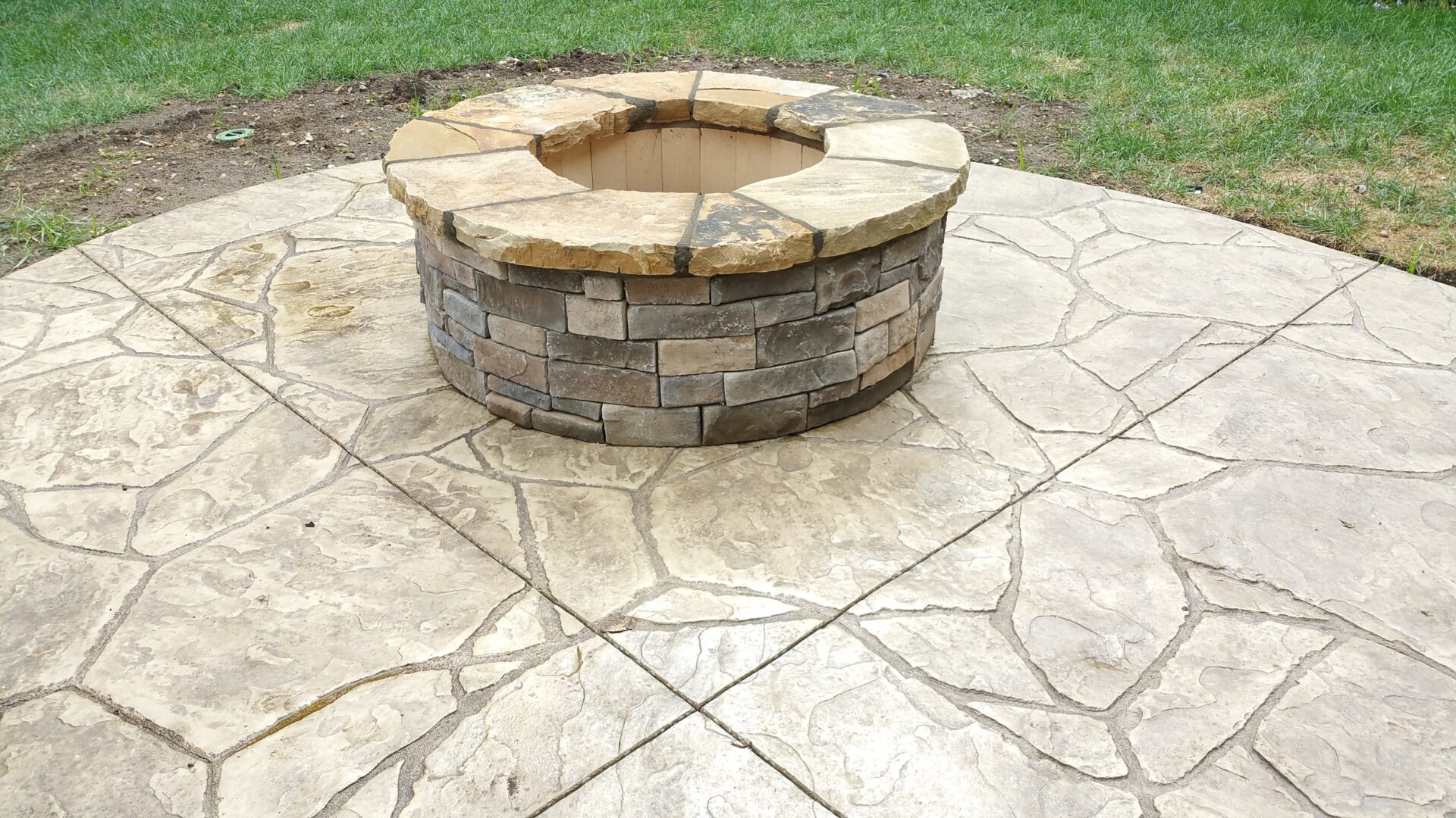 Stone fire pit on a stamped concrete patio.