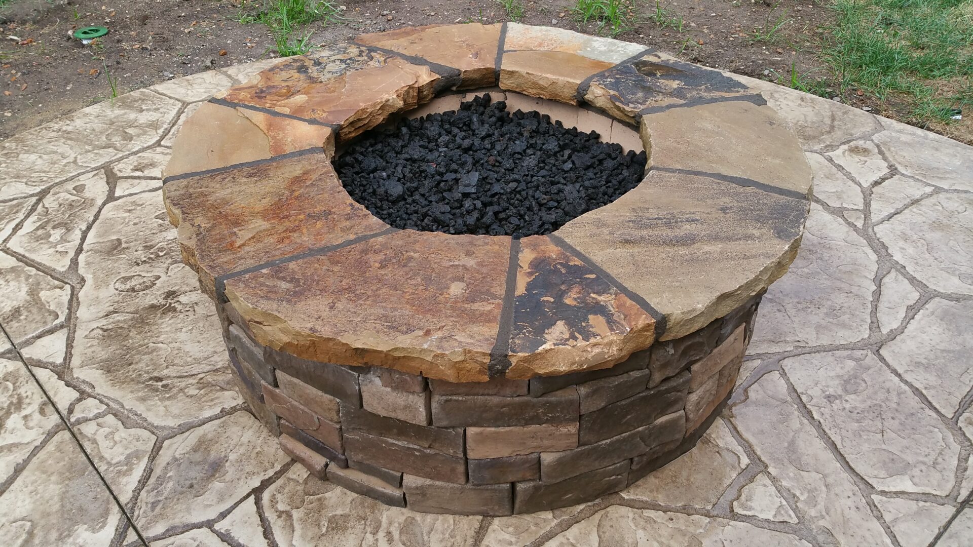 A stone fire pit with black coals inside.