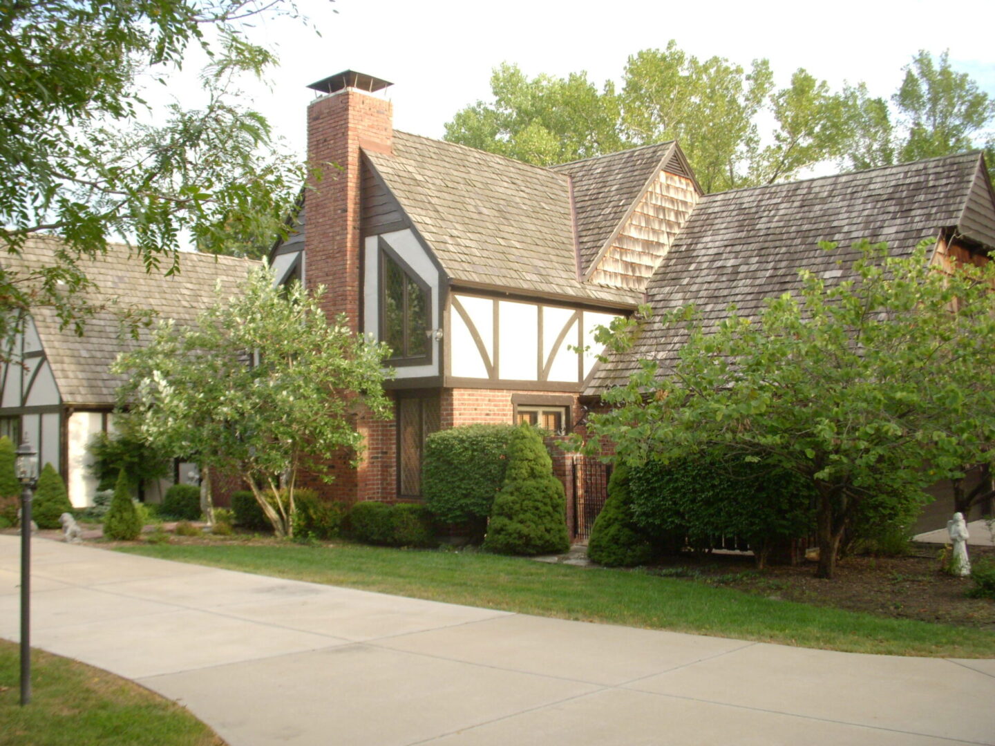 Charming Tudor-style house with lush greenery and a quiet driveway.