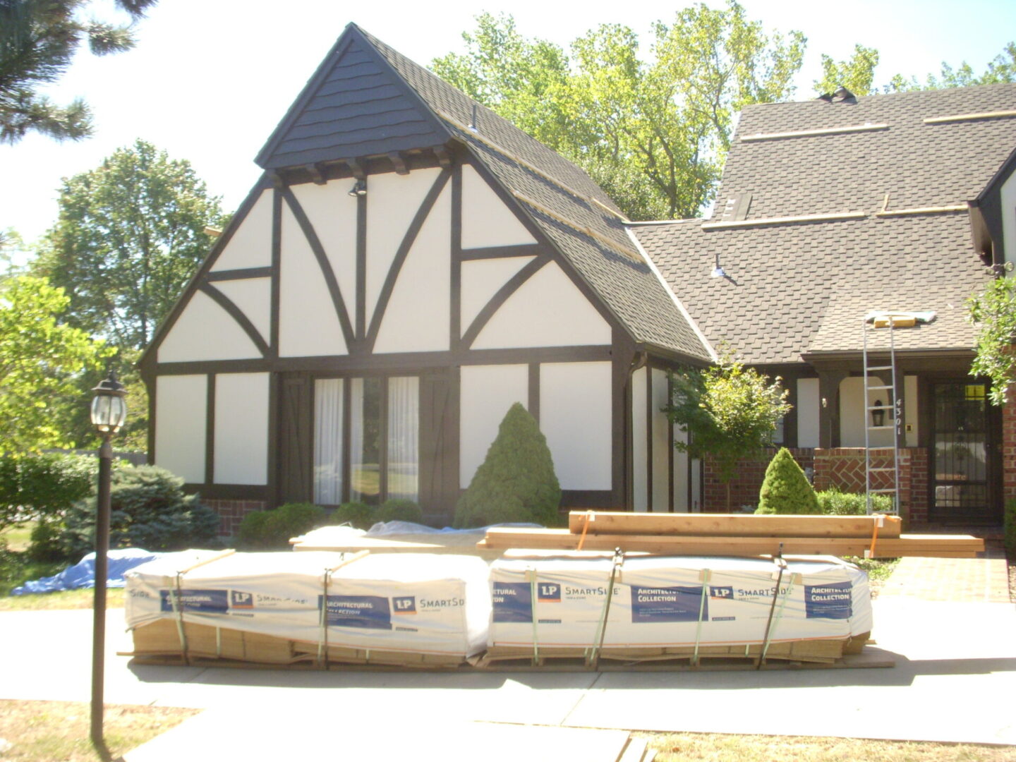 Construction materials stacked in front of a Tudor-style house.