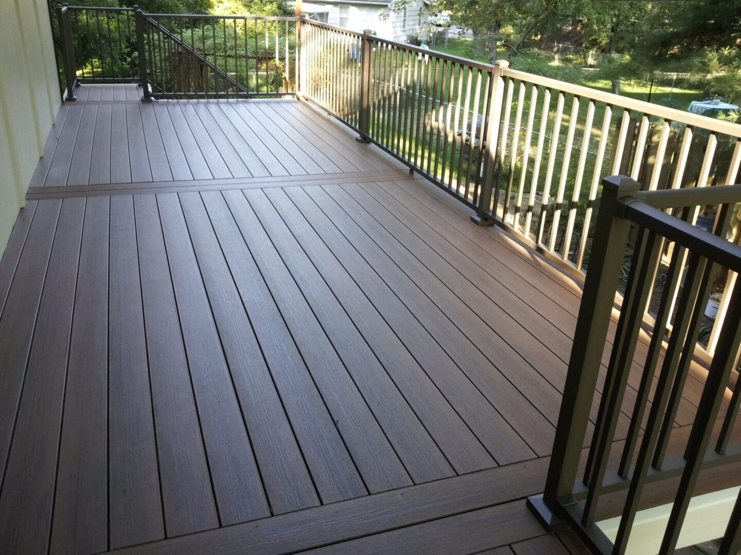 Spacious outdoor deck with brown composite flooring and black railing.