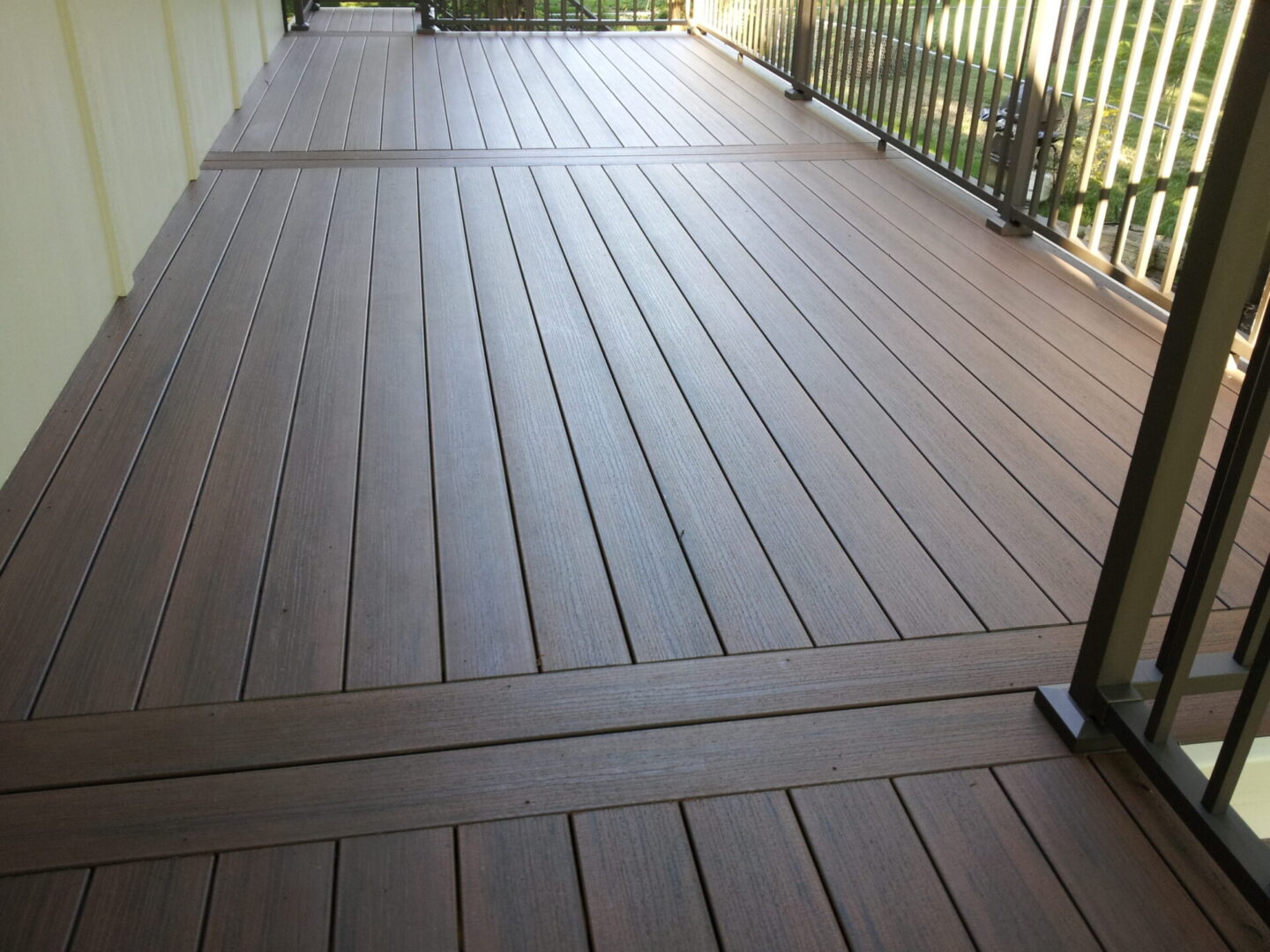 A clean, brown composite deck with parallel planks and a railing.