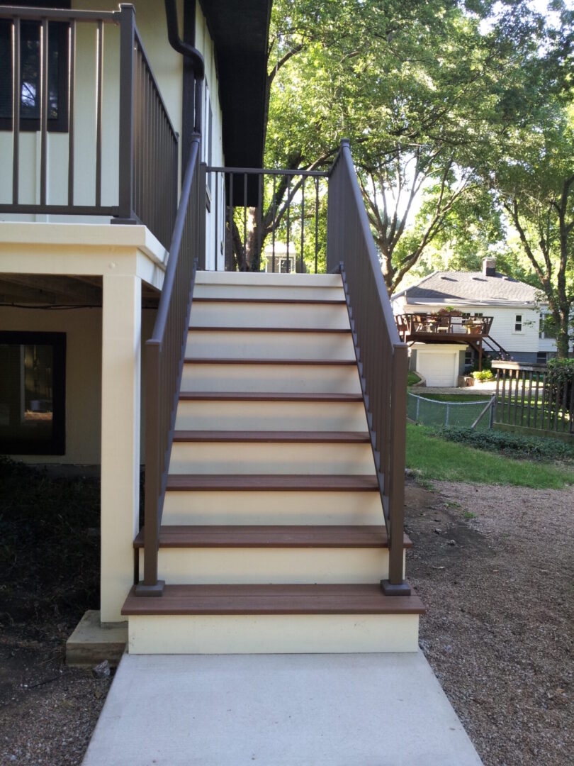 A set of wooden stairs with brown handrails leading up to a porch.