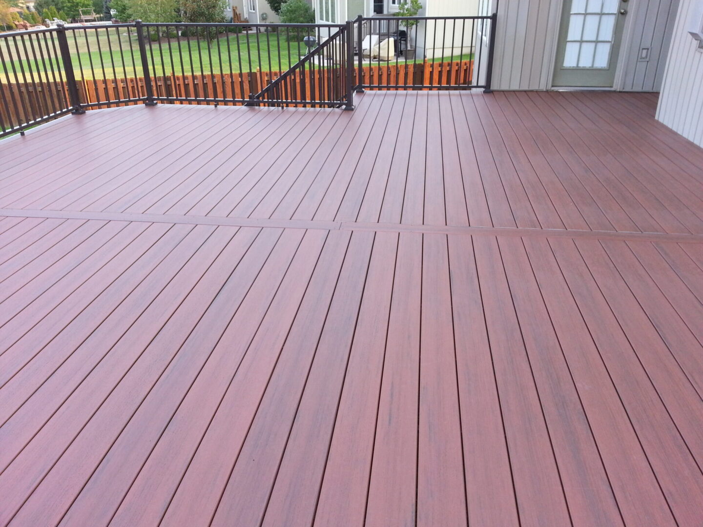 Newly installed reddish-brown wooden deck with metal railing.