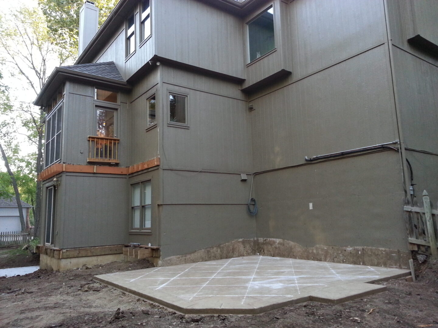 Concrete slab foundation beside a gray building with a balcony above.