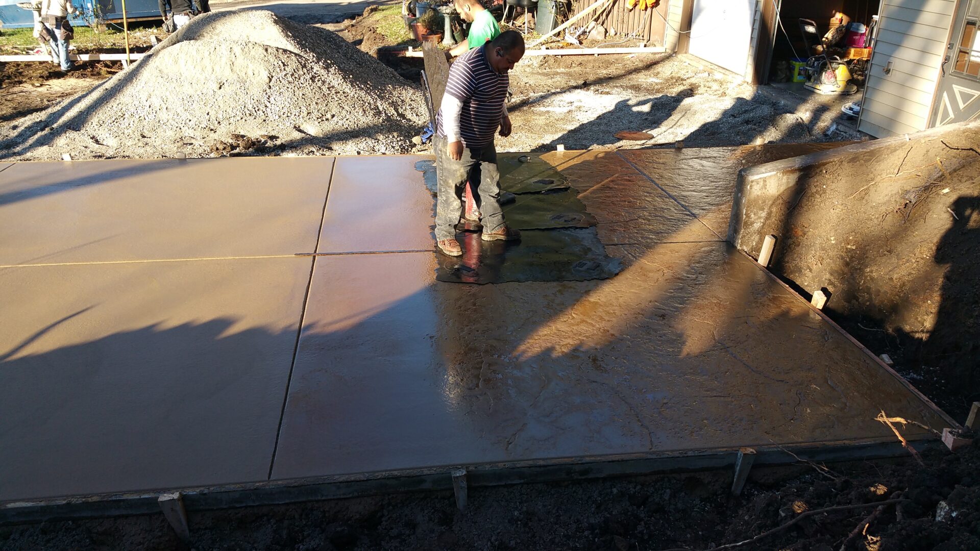 Workers smoothing freshly poured concrete outside.