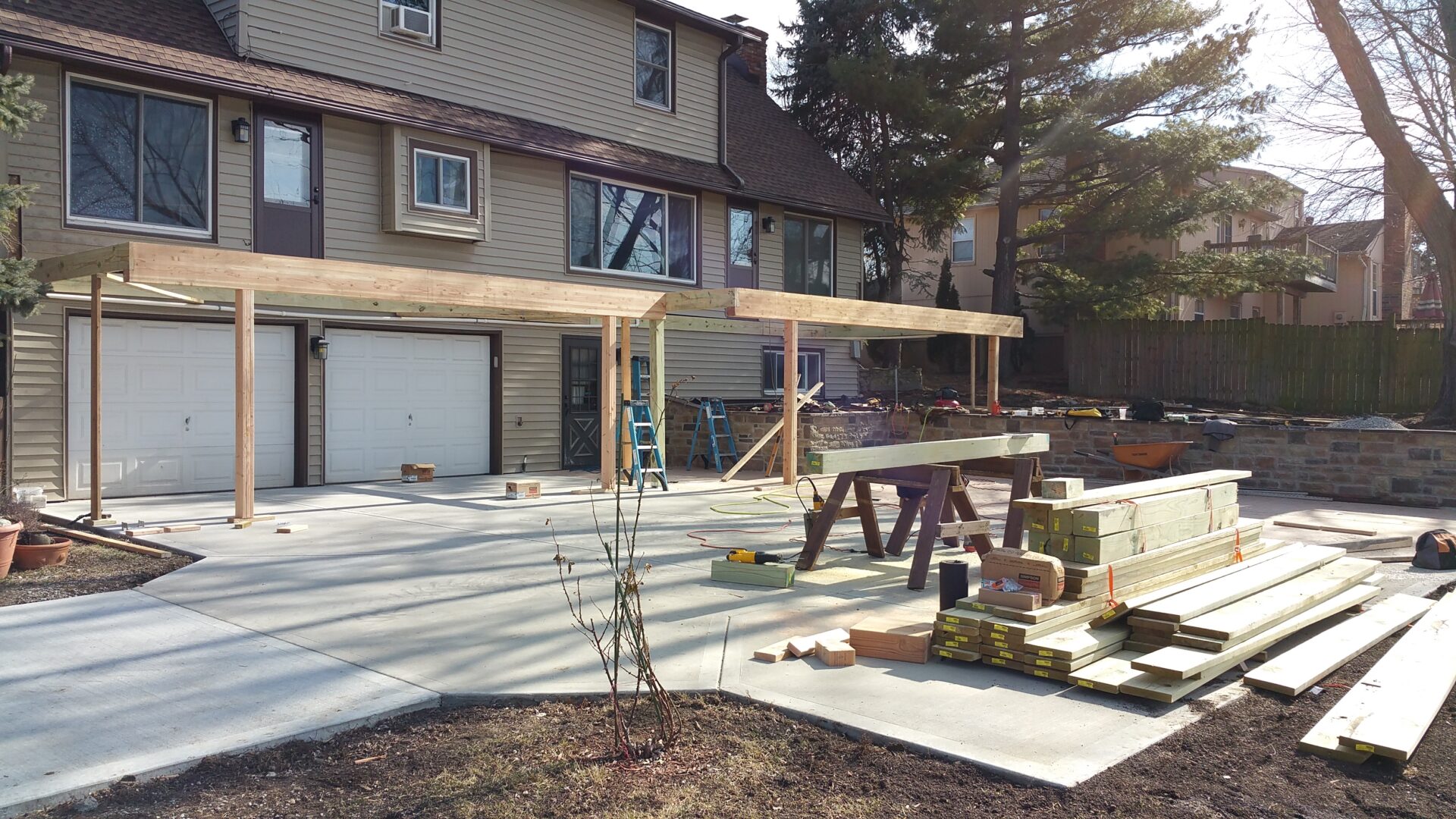 Construction workers building an outdoor wooden structure beside a house.