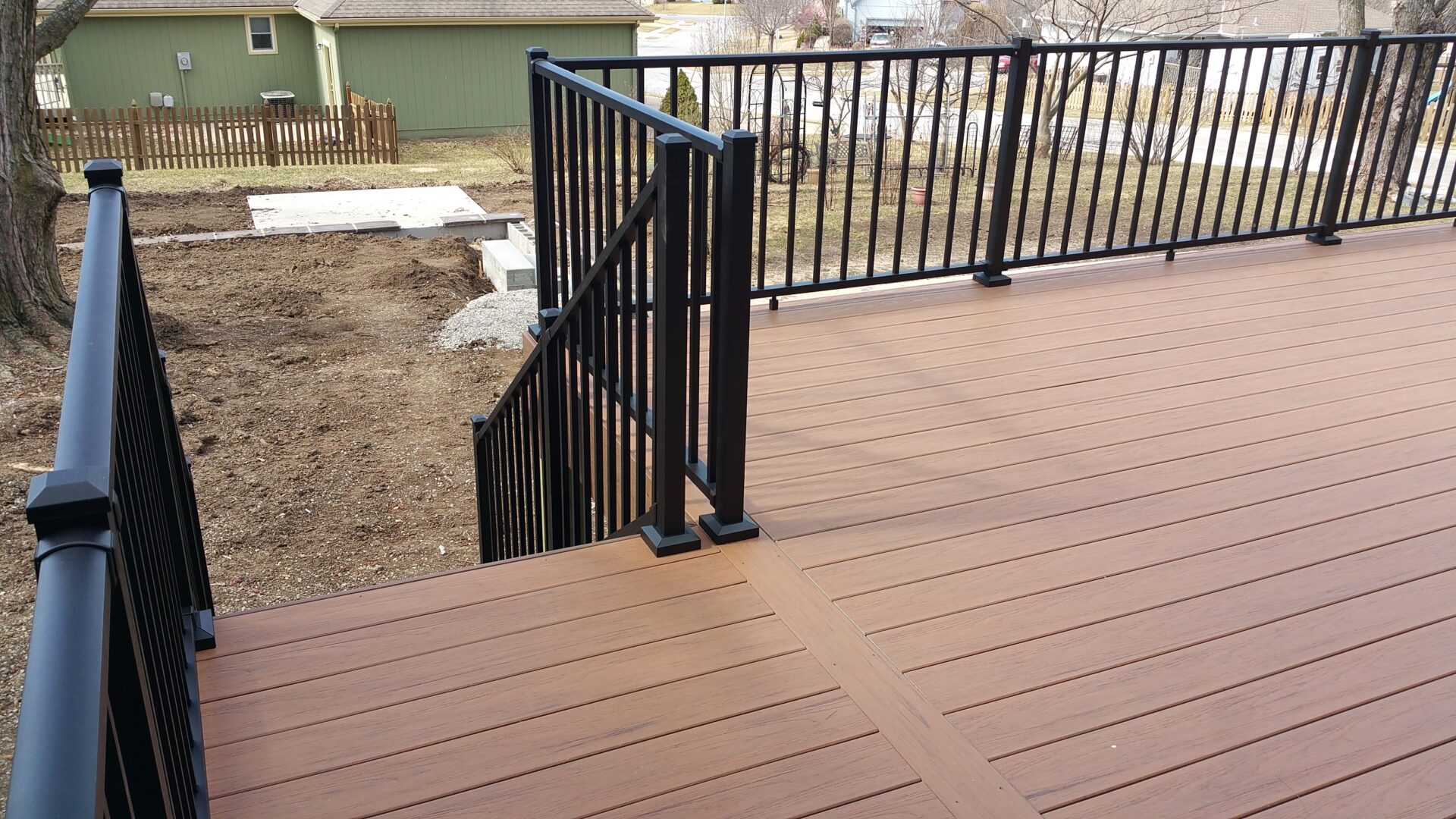 Modern deck with brown composite flooring and black metal railing.