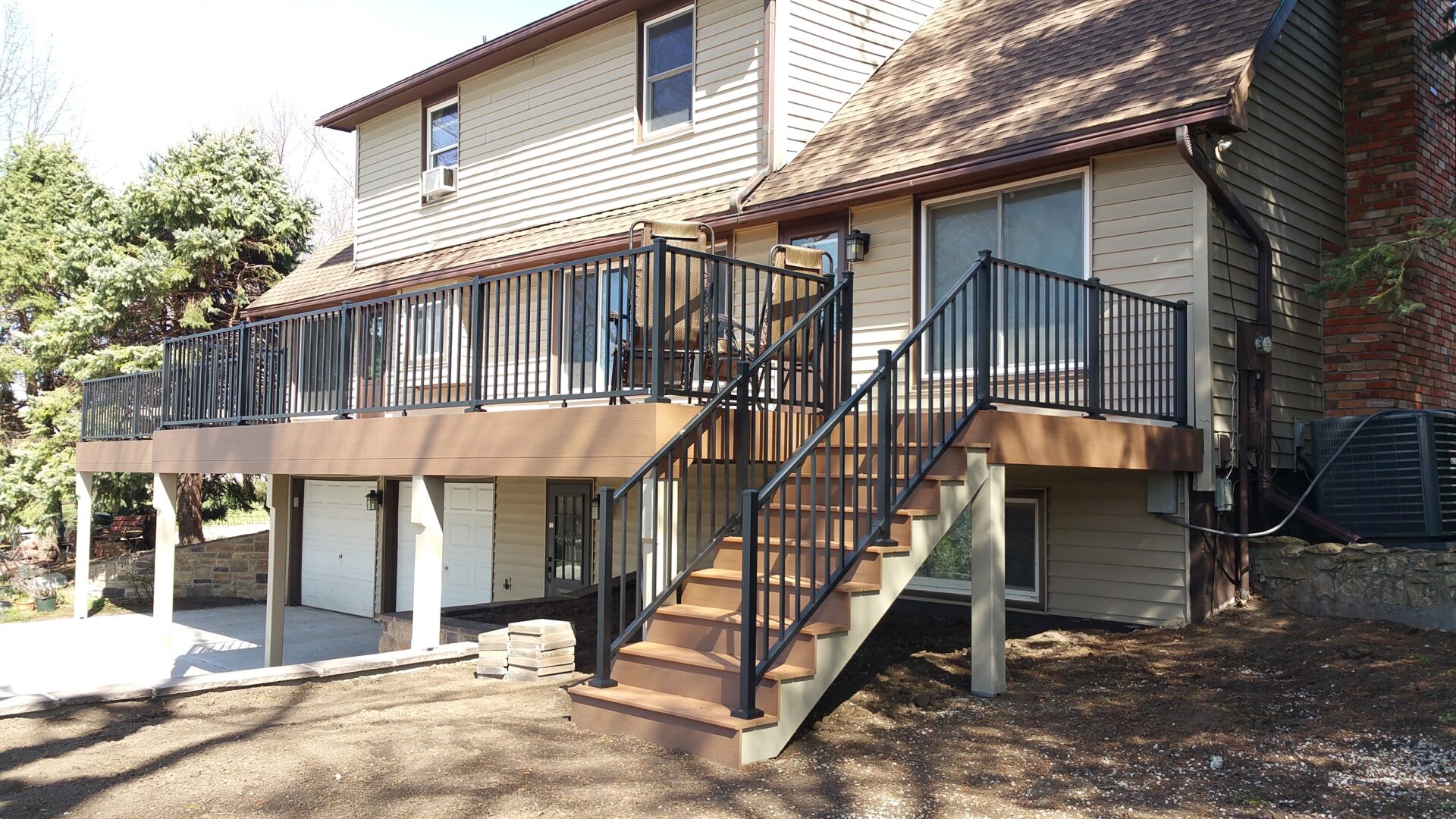New wooden staircase with metal railings leading to a house's elevated entrance.