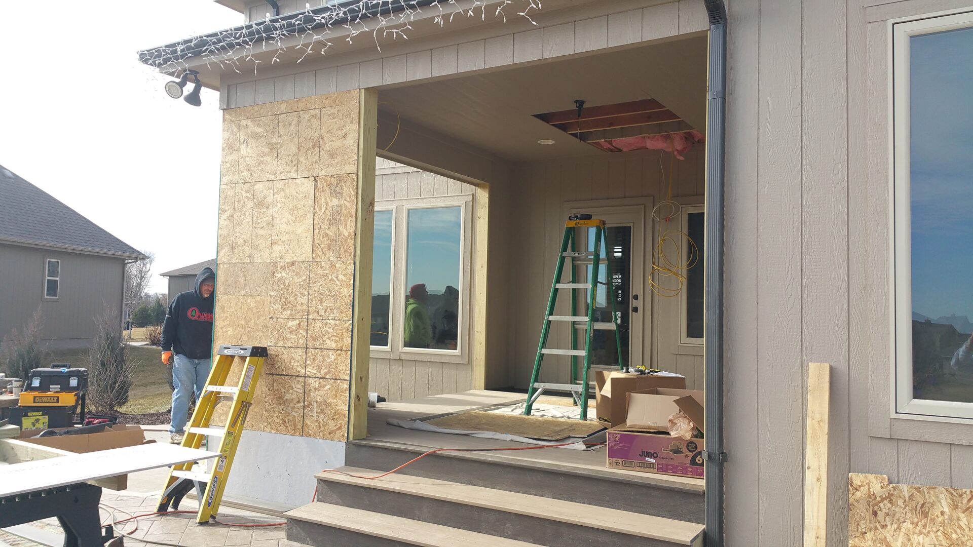 Construction site with ladders and building materials near a windowed entrance.