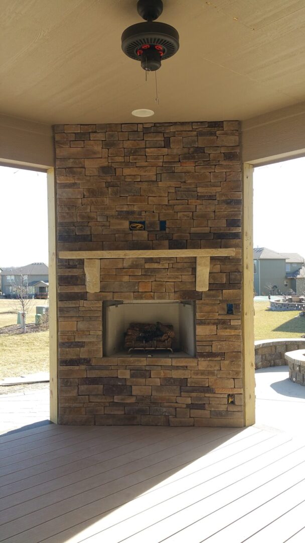 Outdoor stone fireplace with a mantel in a backyard.
