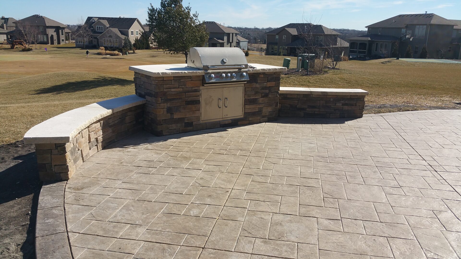 Outdoor stone barbecue grill with spacious patio and scenic backyard.