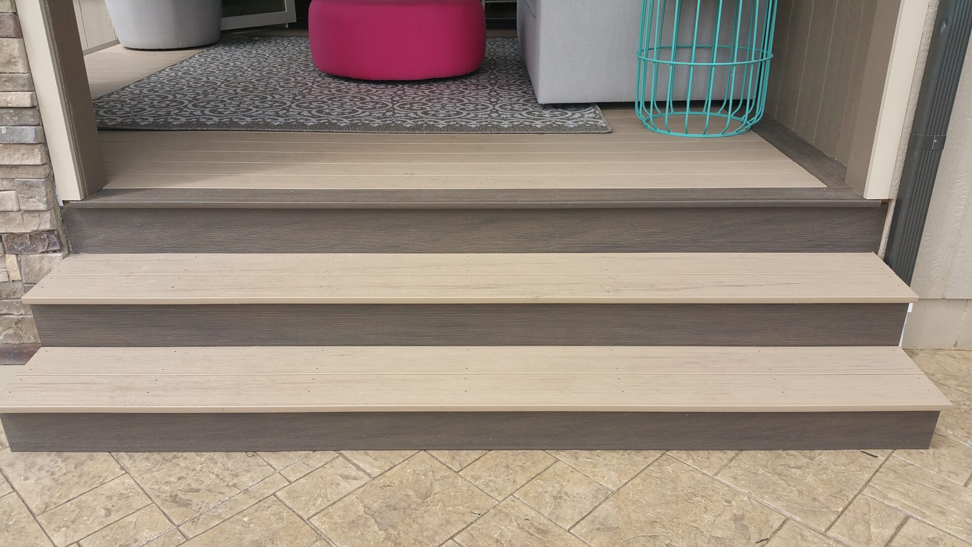 Wide beige stairs with a textured gray landing and pink and turquoise accents.