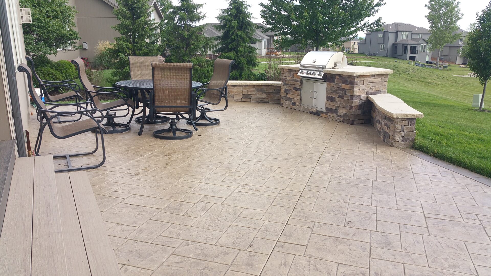 Spacious outdoor patio with stone grill and seating area.