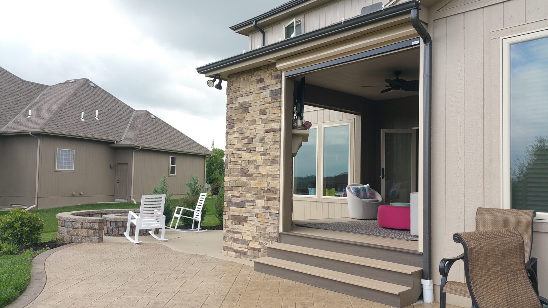 Stone house with open patio door and outdoor seating area.