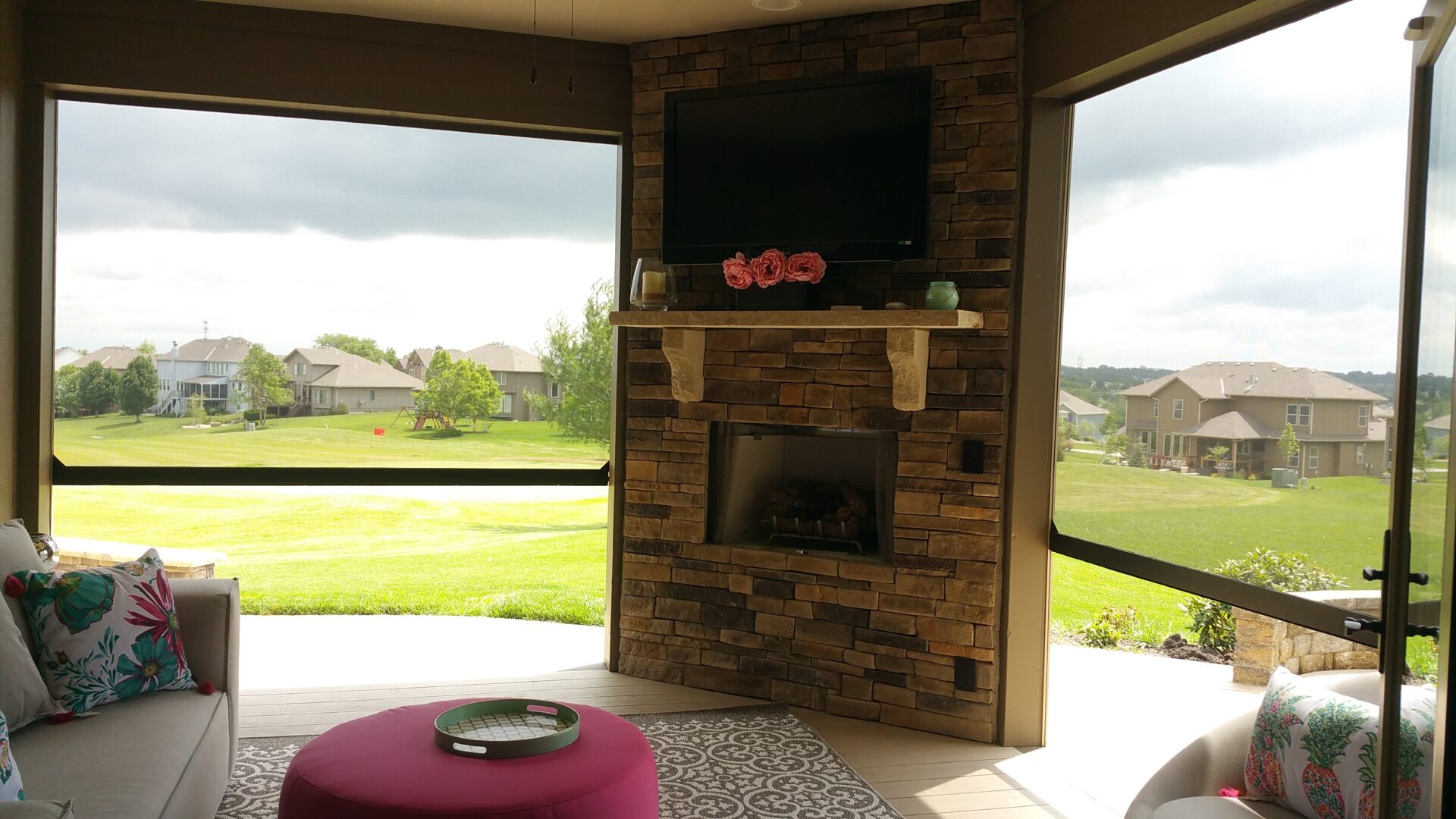 Cozy outdoor stone fireplace with TV and scenic view.