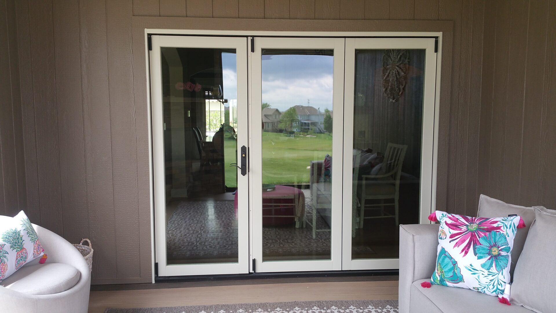 Sliding glass door with a view of a green lawn and houses.