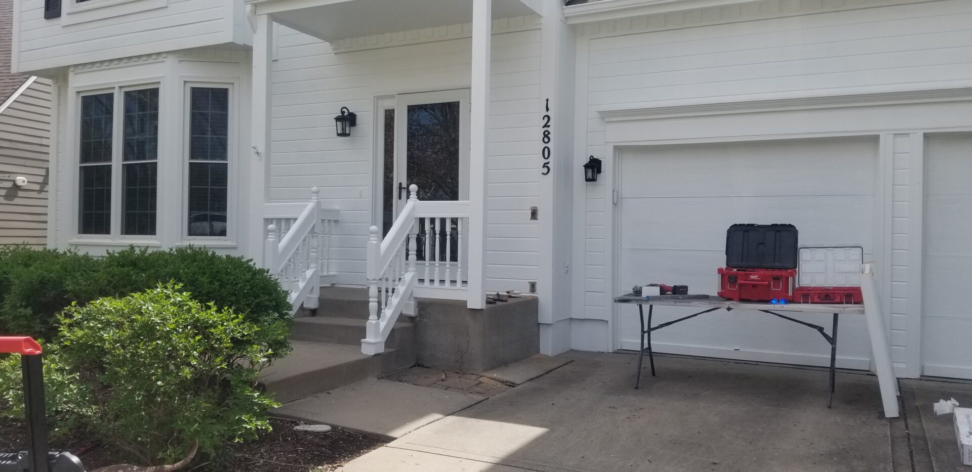 White house entrance with stairs and garage door.