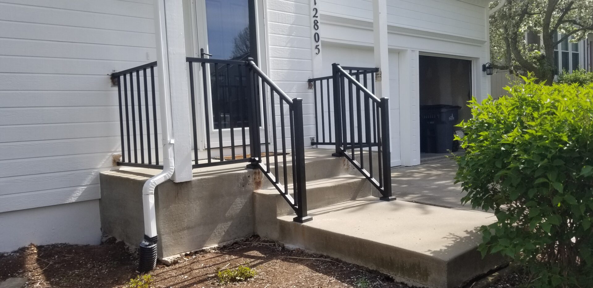 Black metal railings installed on a small concrete staircase.