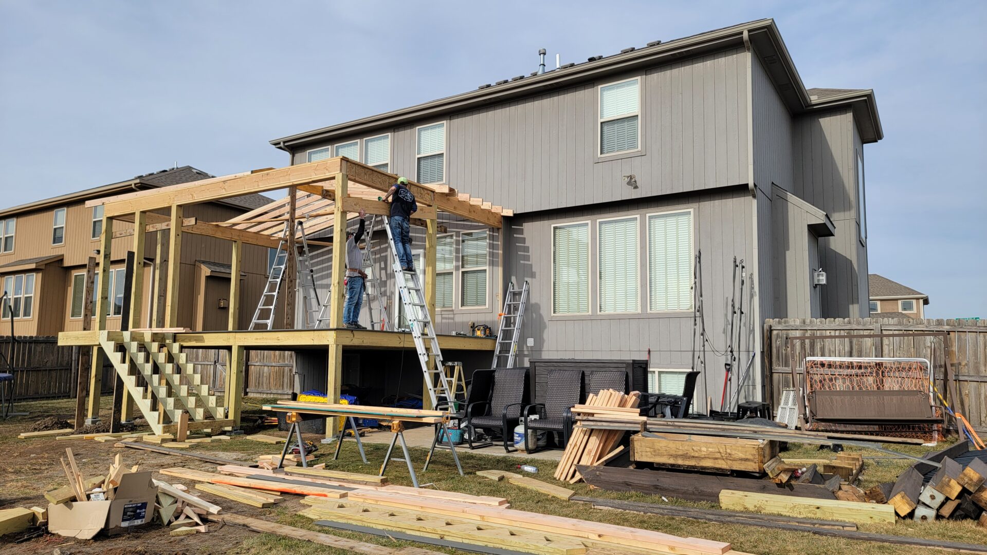 Construction workers building a wooden deck on a house's backyard.
