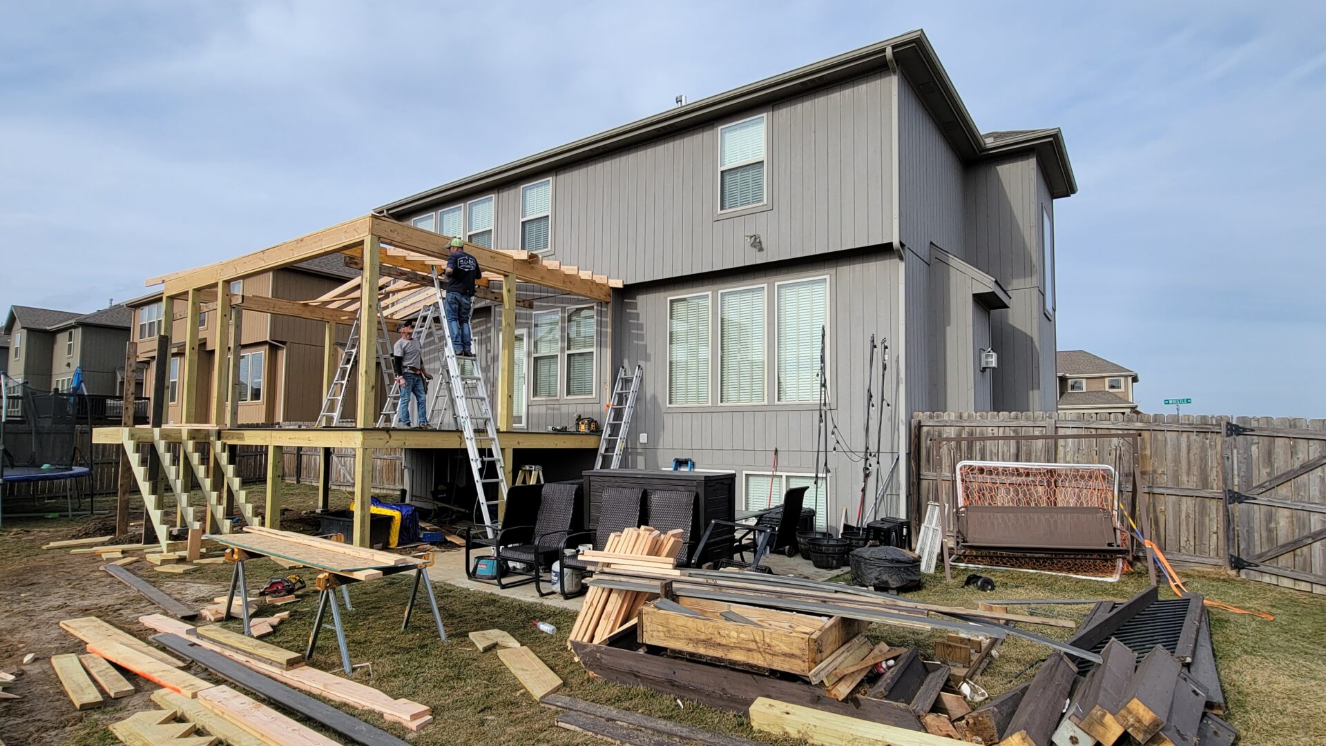 Construction workers building a wooden deck on a modern house.