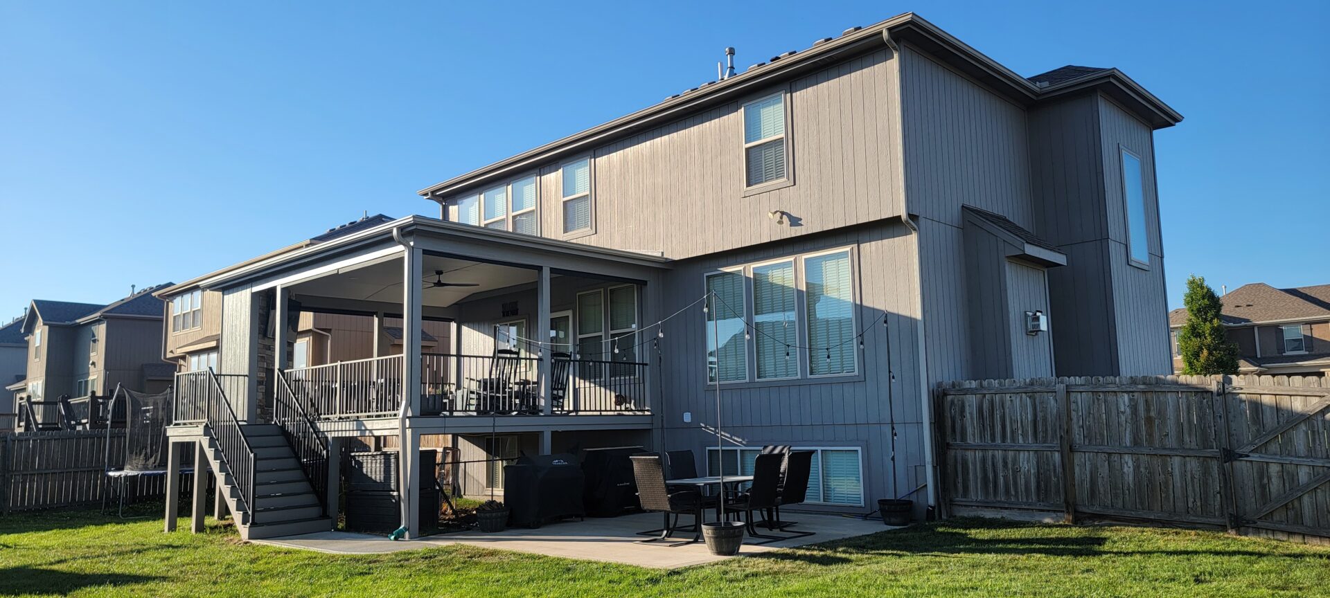 A modern two-story house with a patio and outdoor seating area.