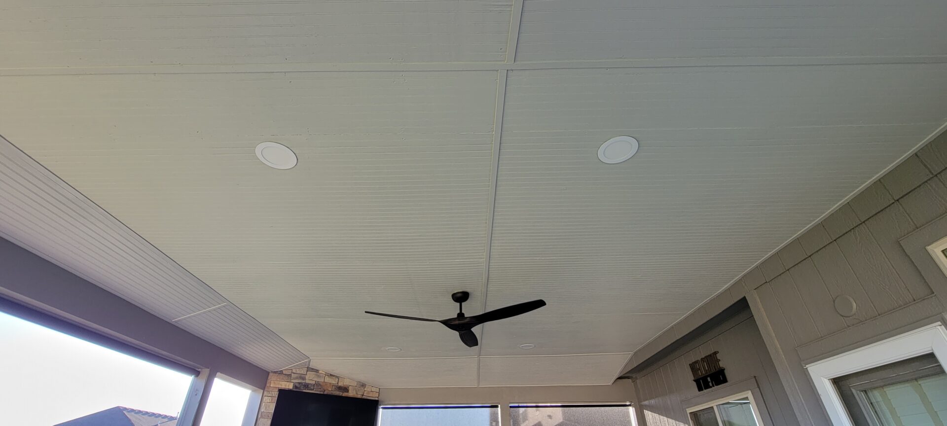 Black ceiling fan mounted on a white ceiling with two round light fixtures.
