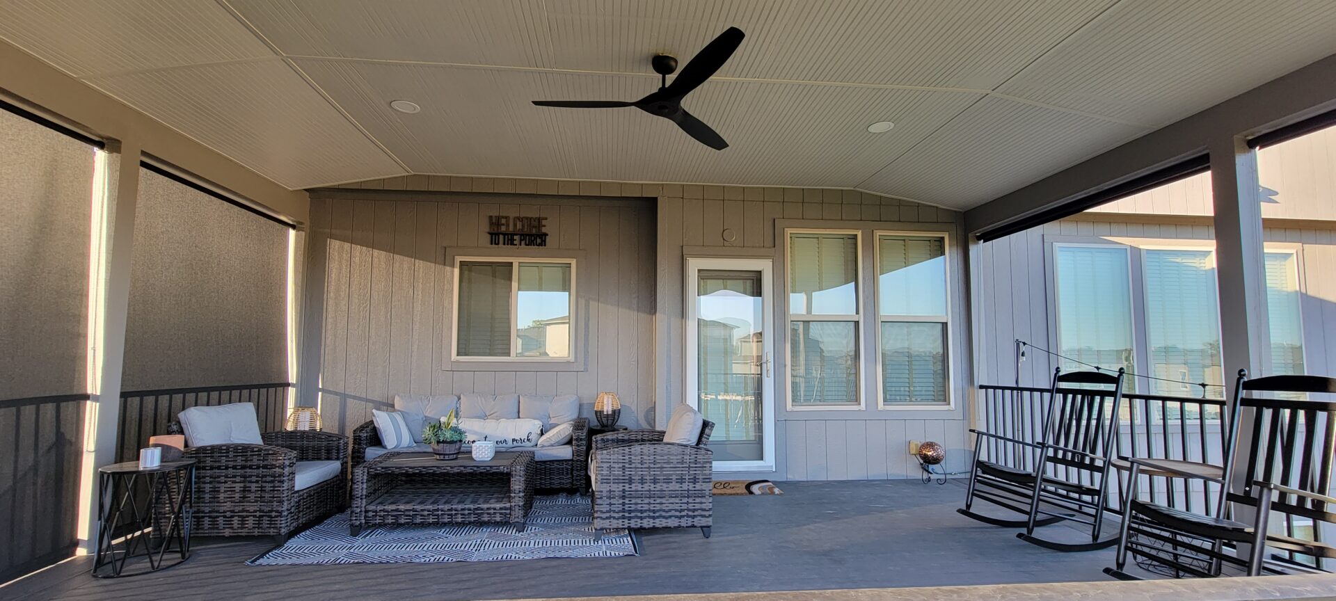 Cozy outdoor patio with wicker furniture and a ceiling fan.