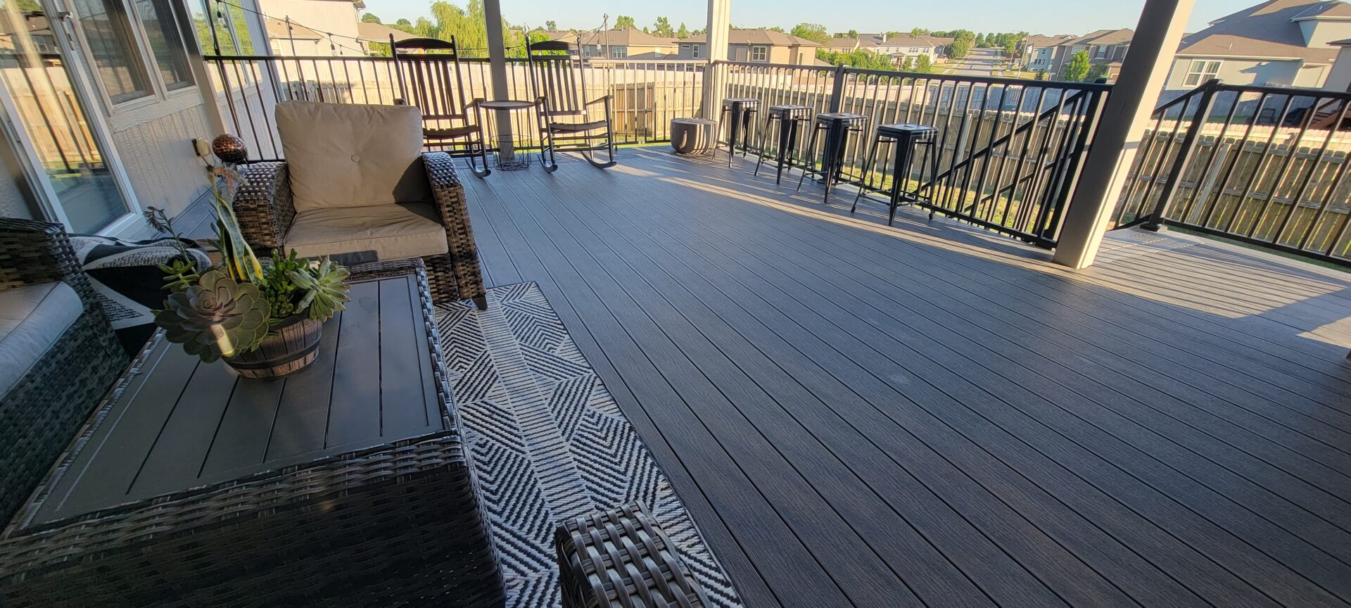 Spacious outdoor deck with stylish patterned rug and comfortable seating.