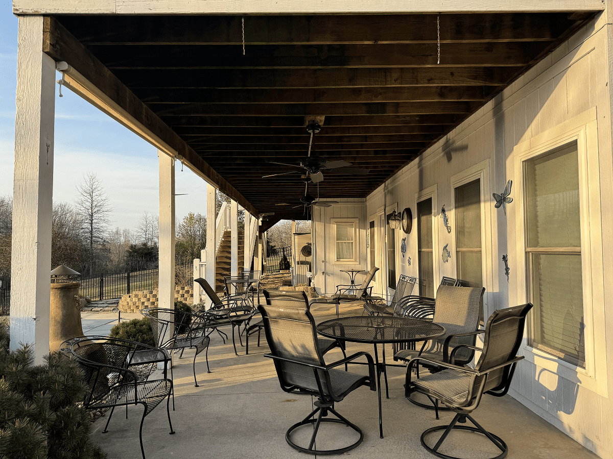 Outdoor patio with metal chairs and tables under a wooden ceiling.