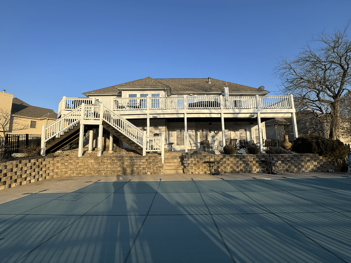 A large house with a wooden deck under construction on a sunny day.