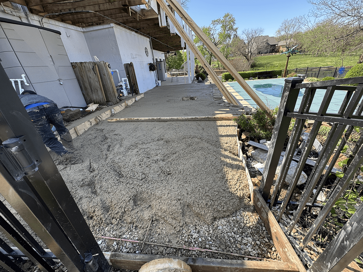 Fresh concrete being poured and leveled on a driveway under construction.