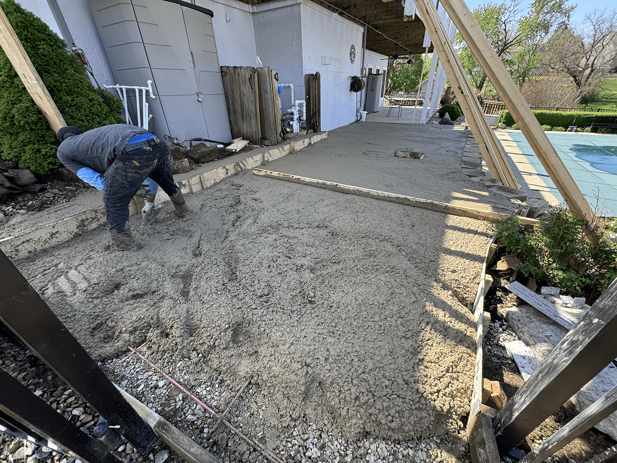 Workers laying concrete on a building's outdoor area under construction.
