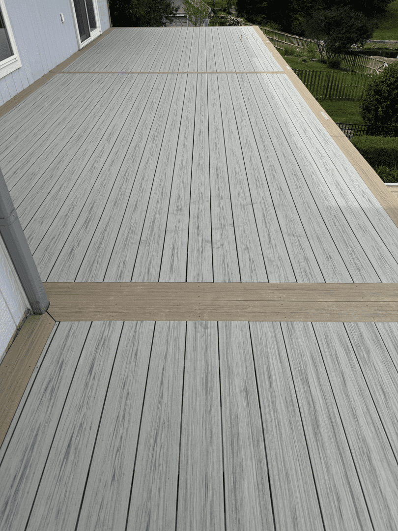 A modern outdoor deck with light gray wooden planks and a beige accent strip.