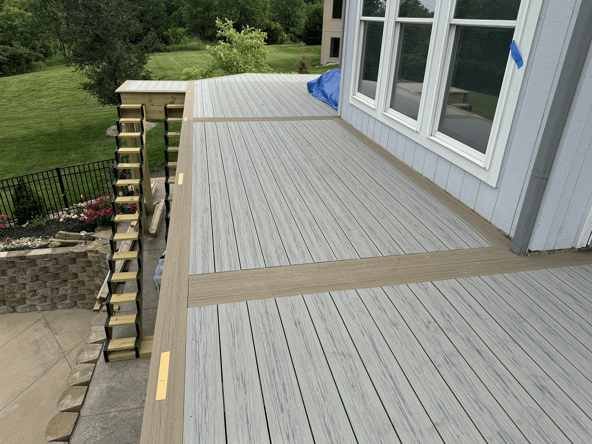 A newly painted wooden deck with gray and beige tones beside a house.