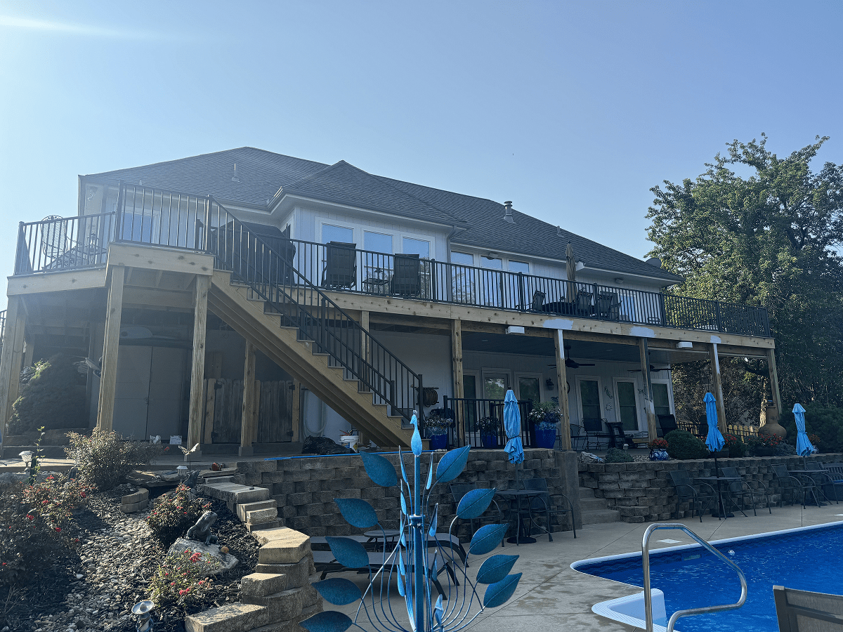 A large house with two levels and a pool in the backyard under a clear sky.