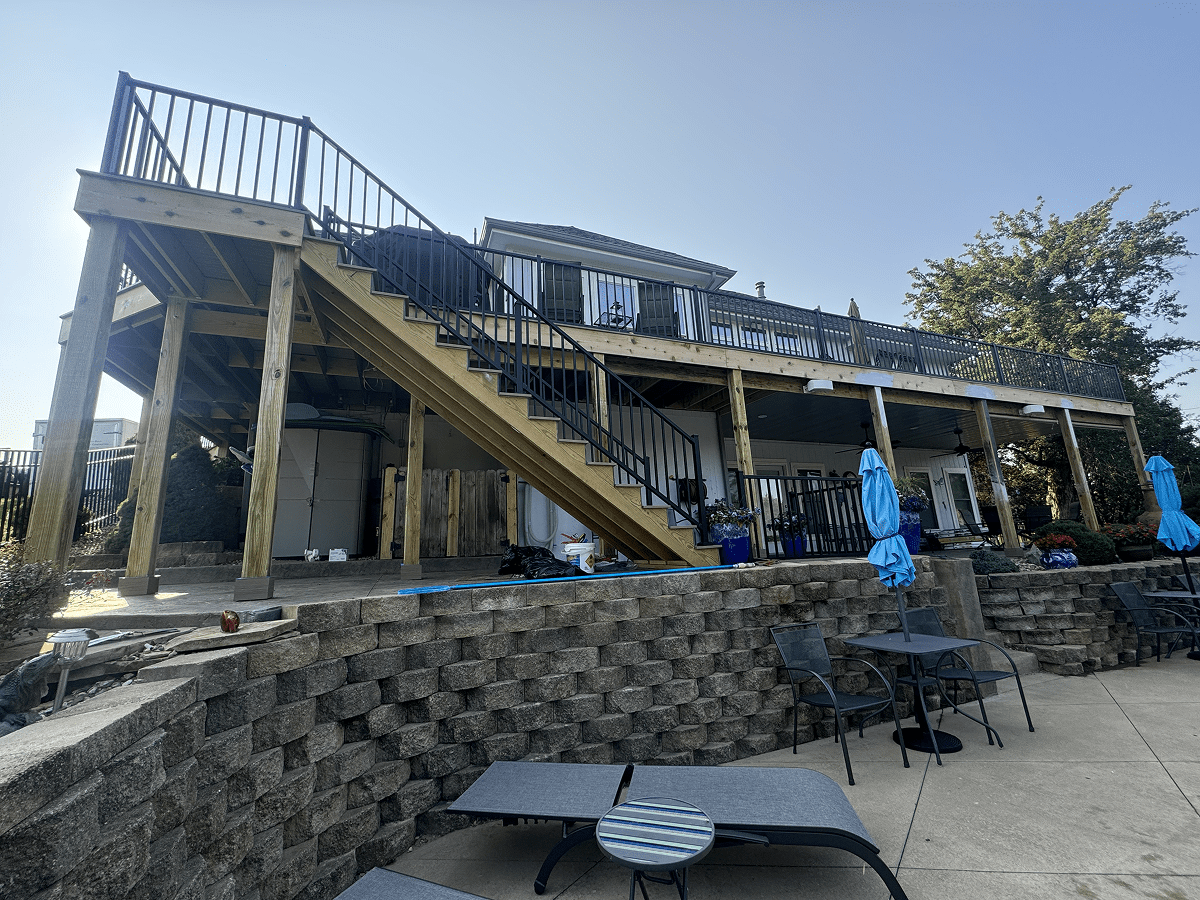 Outdoor seating area with umbrellas and stairs leading to a balcony.