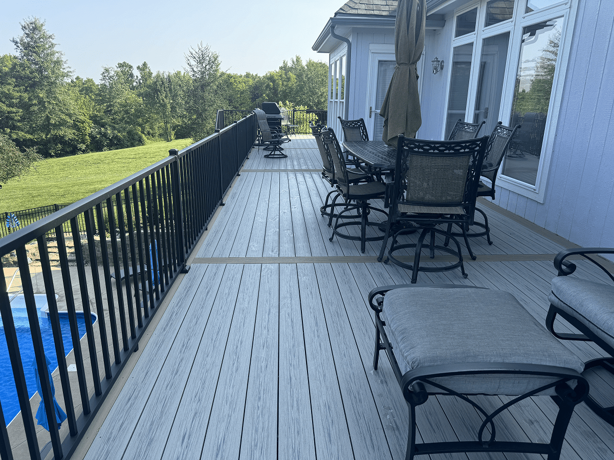 Spacious deck with outdoor seating and umbrella overlooking greenery.
