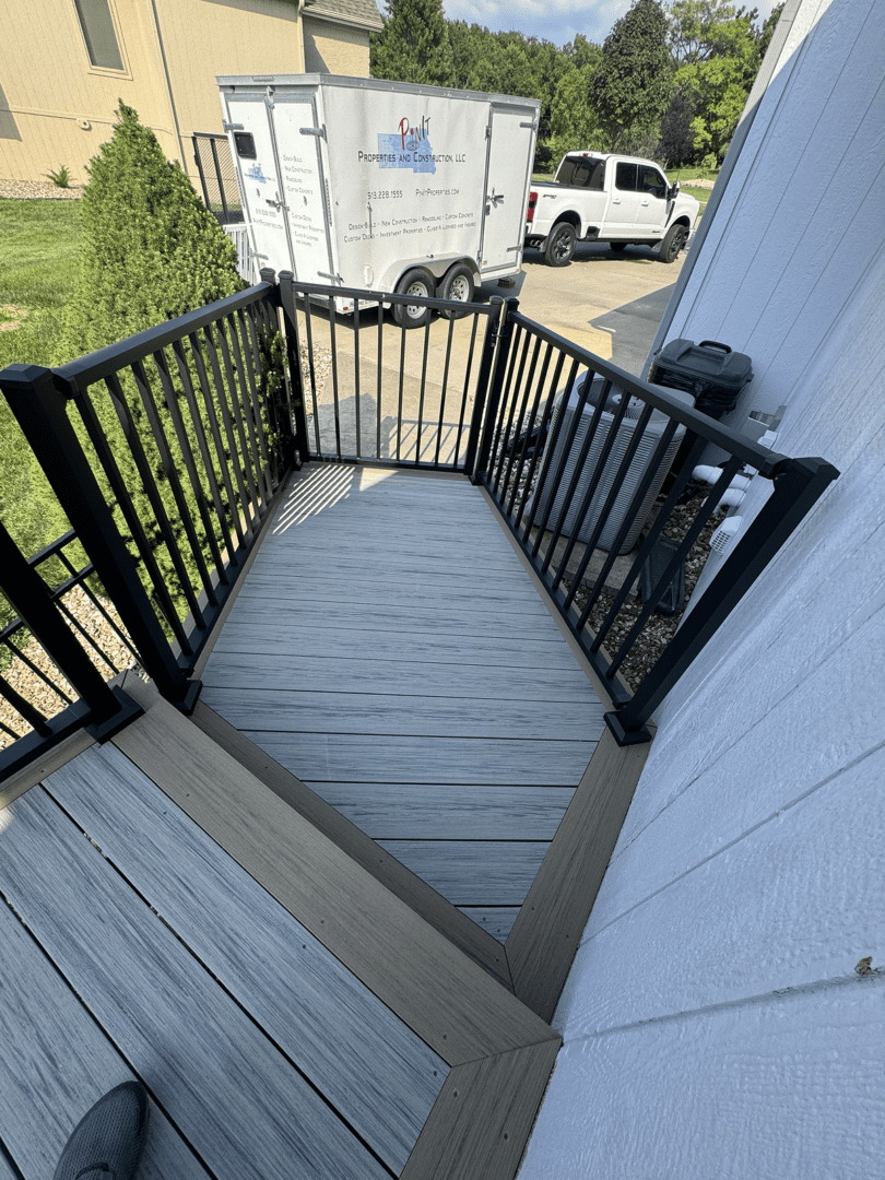 A small porch with black metal railings and gray wooden floor.
