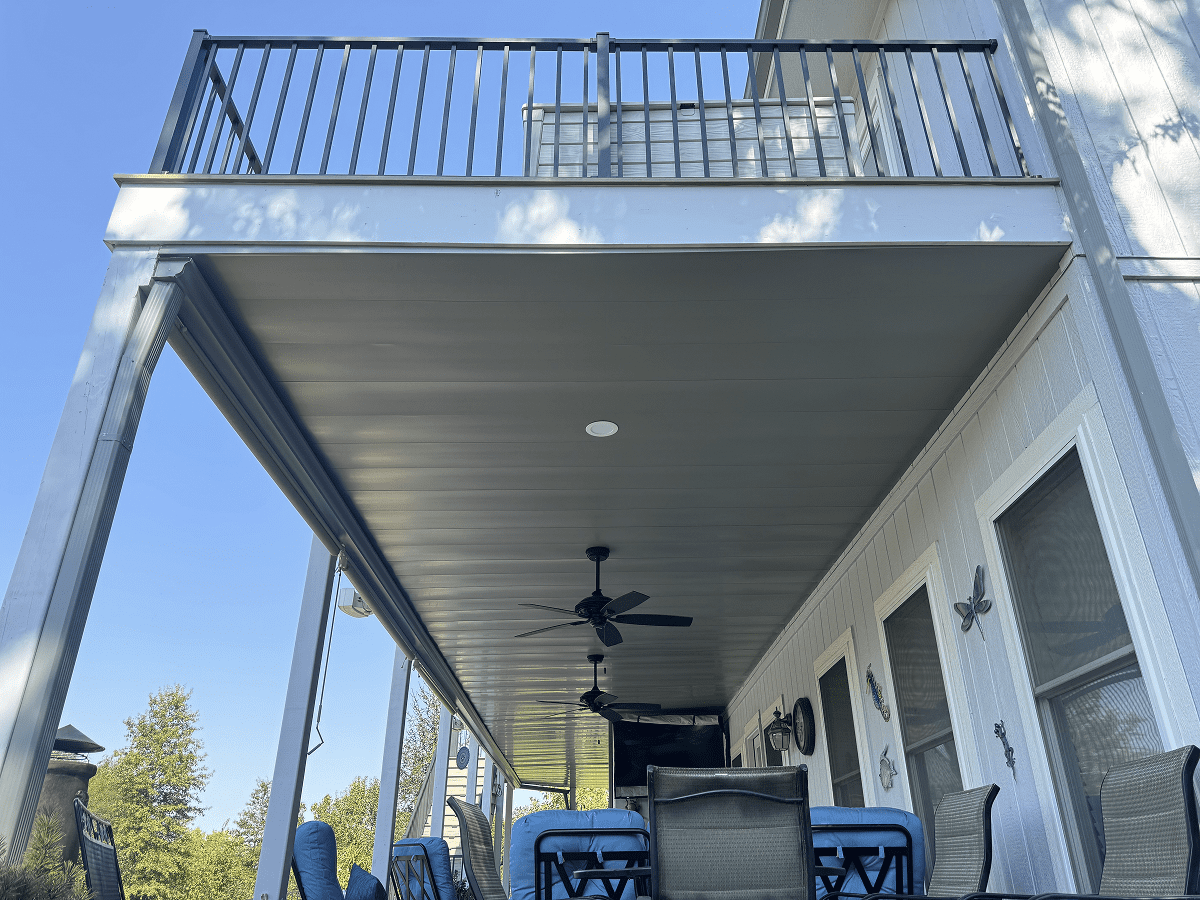 Cozy outdoor patio with ceiling fan and seating under a balcony.