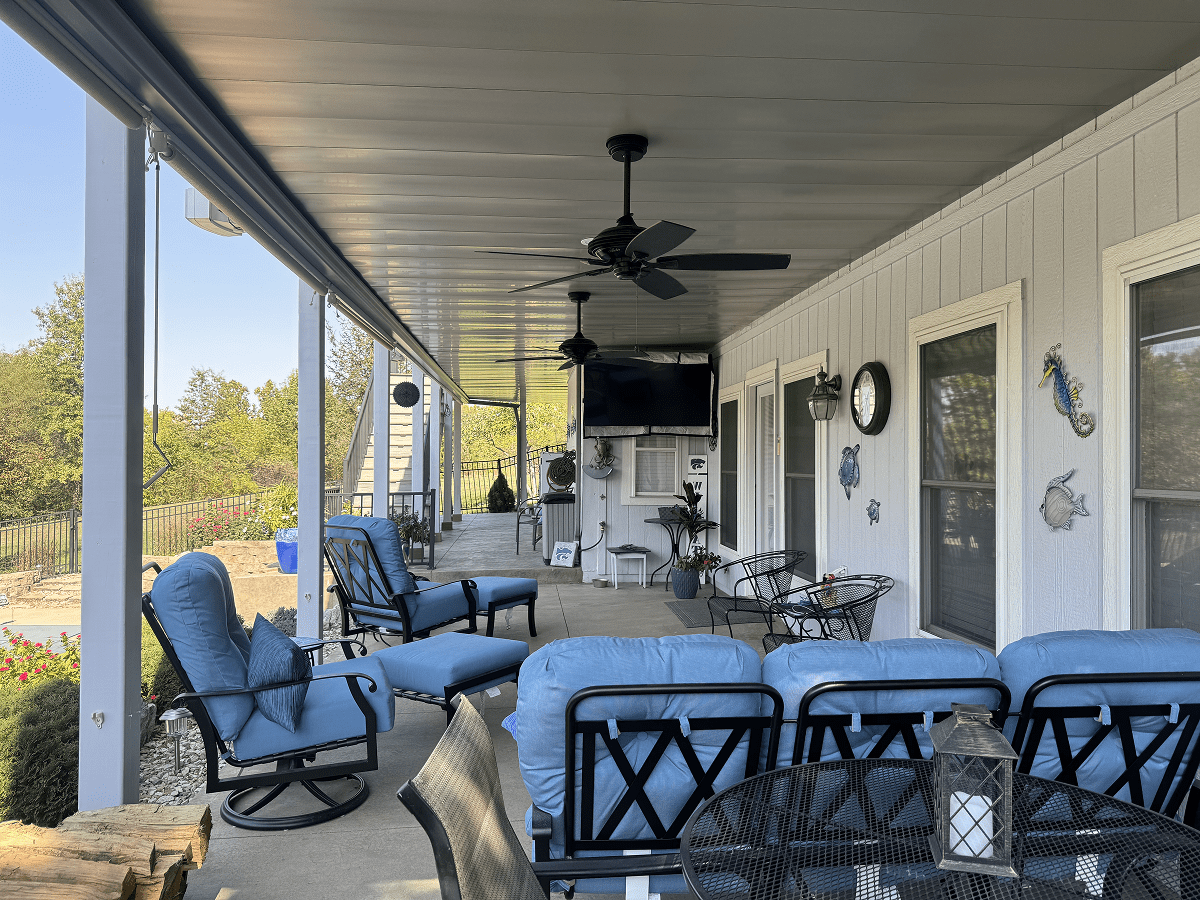 Cozy outdoor patio with comfortable seating, ceiling fan, and a TV.