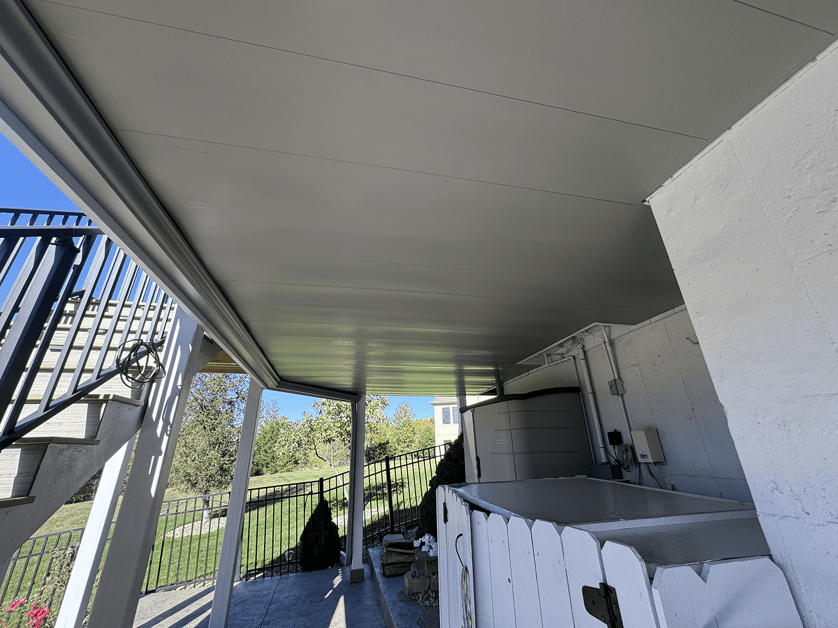 Covered outdoor patio with ceiling fans and a view of the green backyard.