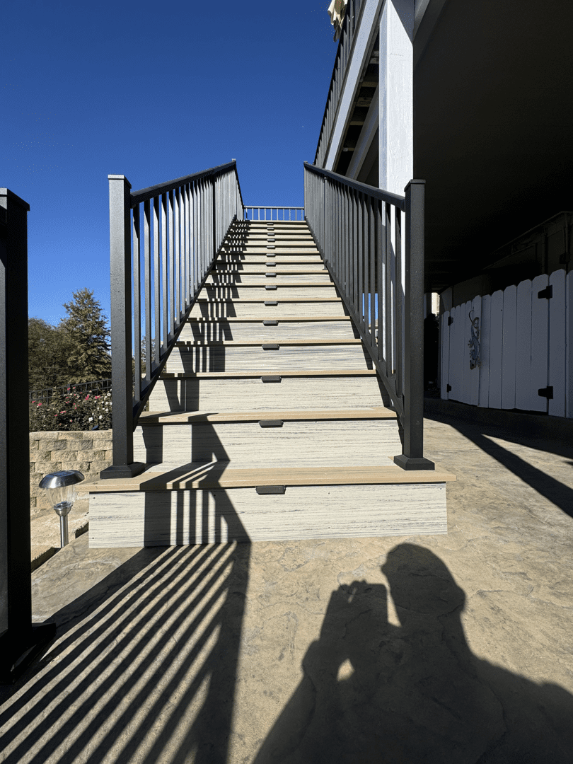 Concrete stairs with metal railings casting shadows under bright sunlight.