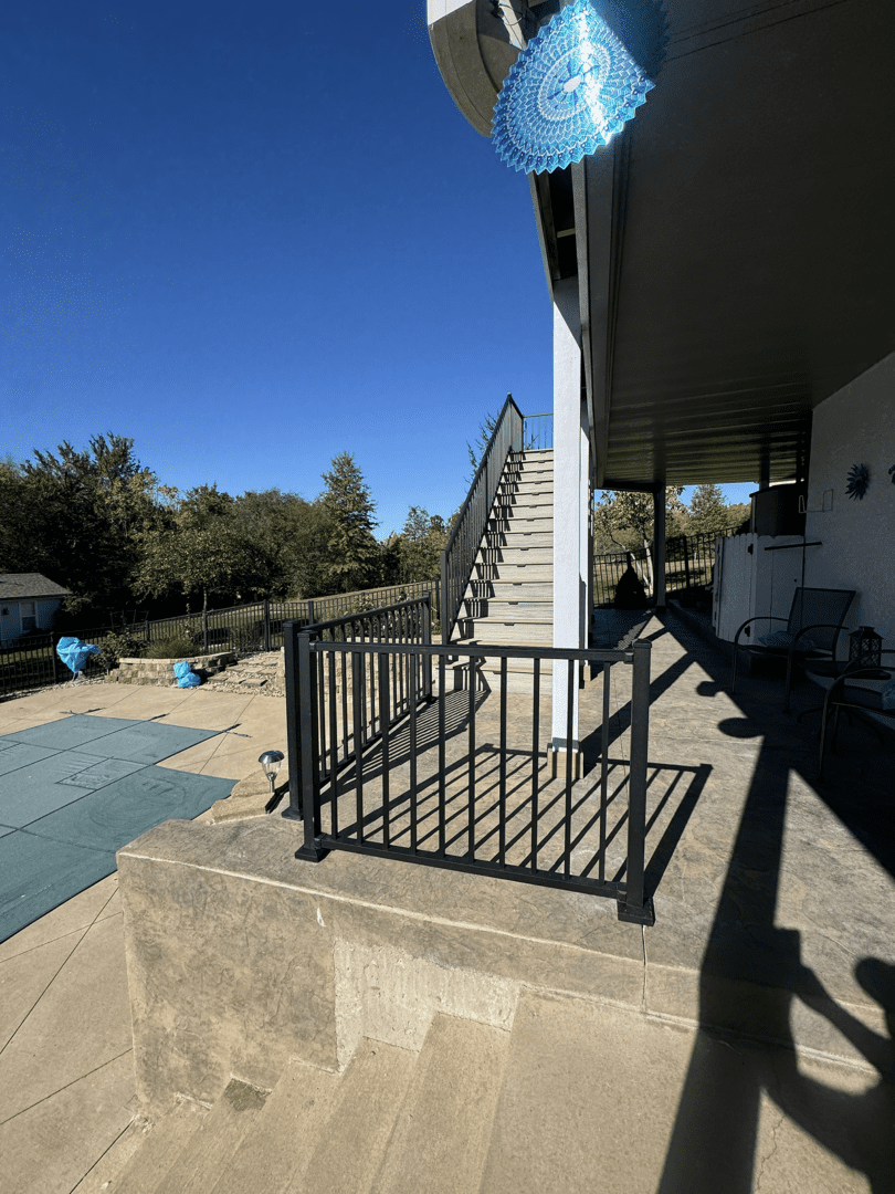 Outdoor patio with stairs, pool, and seating area under a clear blue sky.
