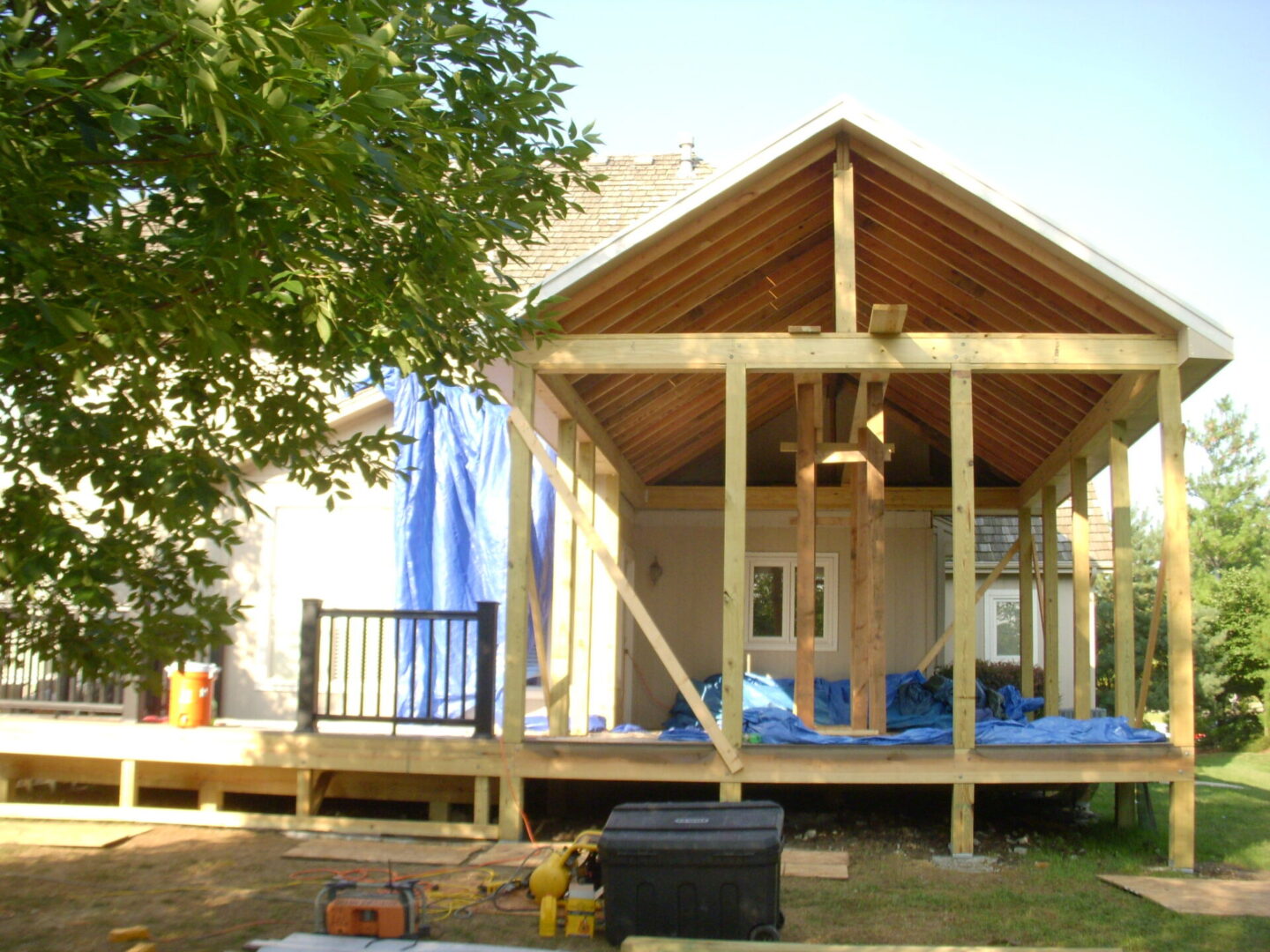Wooden cabin under construction in a sunny outdoor setting.
