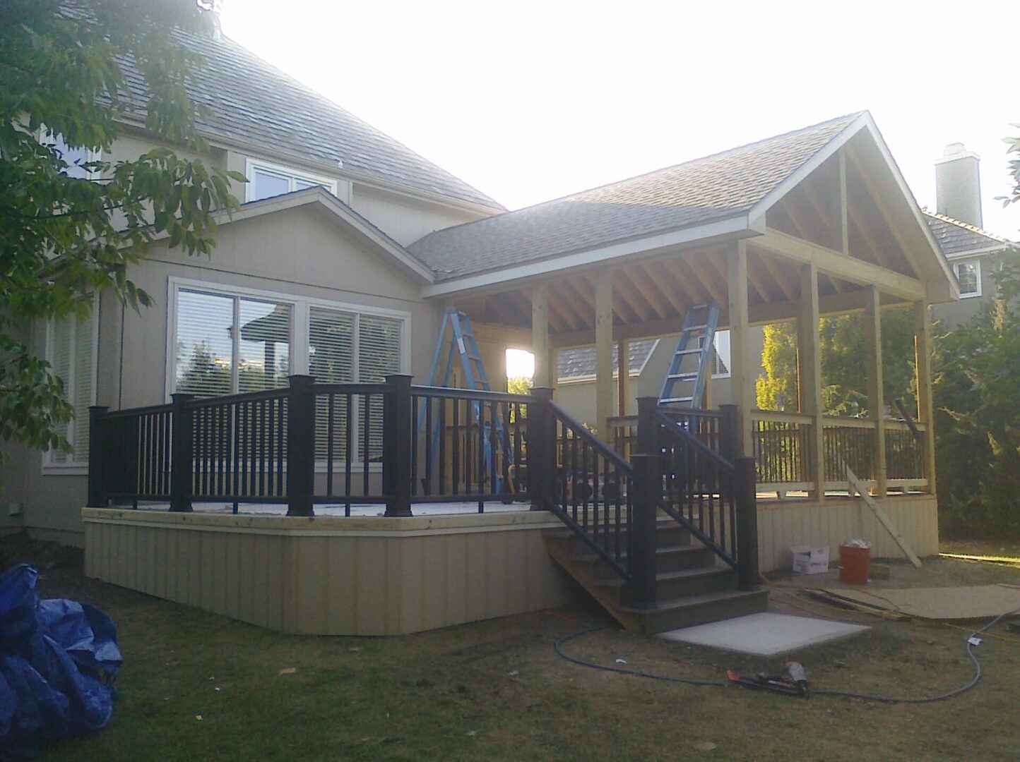 A house with a raised deck and black railing under a cloudy sky.