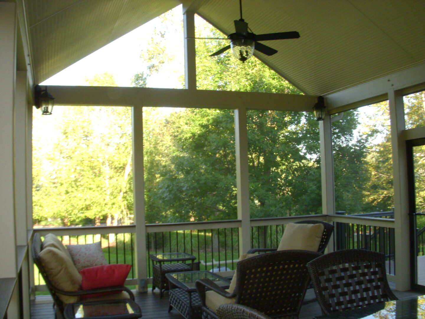 Cozy screened porch with comfortable seating and ceiling fans overlooking a lush garden.