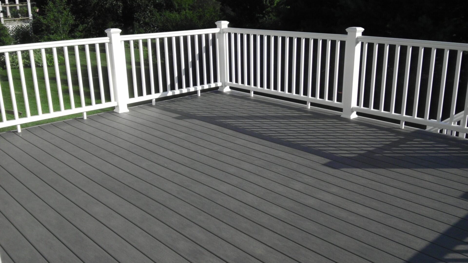 A clean, modern gray deck with white railing on a sunny day.
