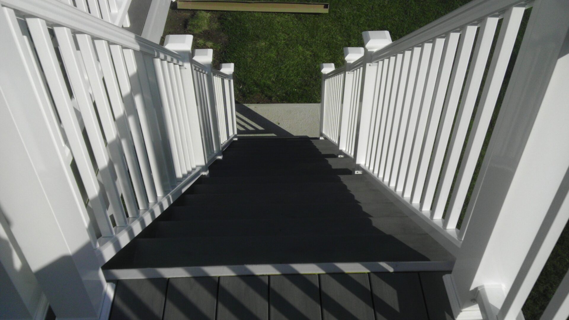 View down a white wooden staircase with shadow patterns.